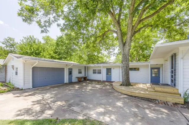 a view of a house with a yard and large tree