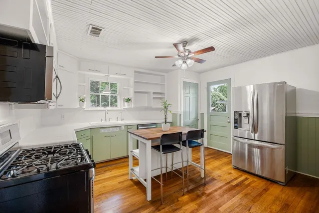 a kitchen with stainless steel appliances granite countertop a refrigerator a sink dishwasher a stove and white countertops with wooden floor