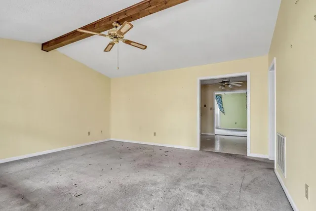 an empty room with a ceiling fan and carpet