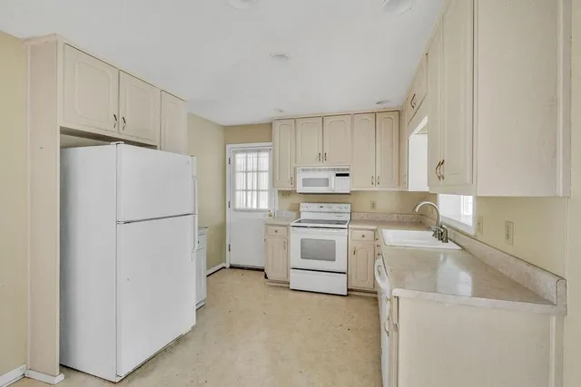 a kitchen with white cabinets and white appliances