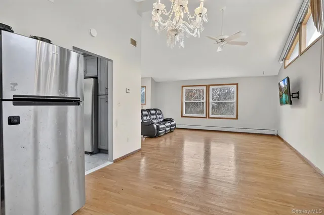 a view of a kitchen with a refrigerator a ceiling fan and a wooden floor
