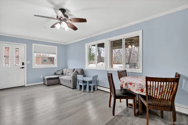 a dining room with wooden floor a chandelier fan a wooden table and chairs