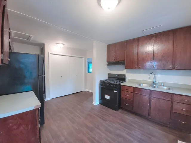 a kitchen with kitchen island granite countertop a sink cabinets and wooden floor
