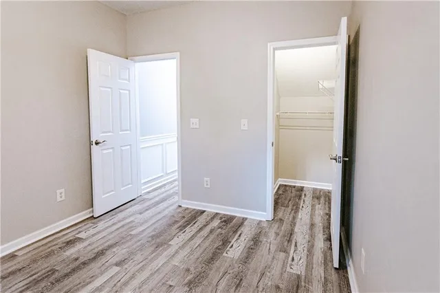 an empty room with wooden floor closet and windows