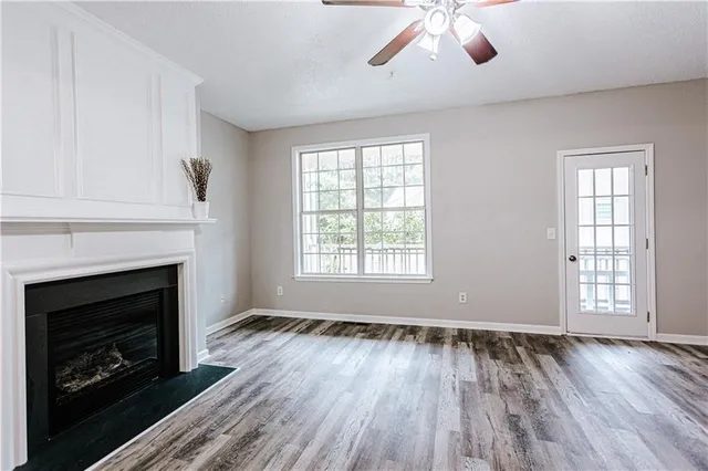 a view of an empty room with wooden floor fireplace and a window