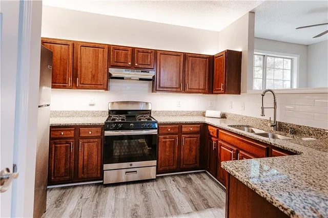 a kitchen with granite countertop a sink stove and cabinets