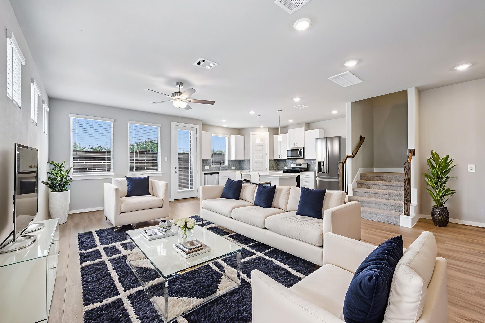 a living room with furniture kitchen view and a large window