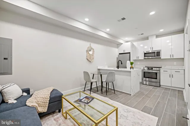 a kitchen with a sink dishwasher a stove and white cabinets with wooden floor