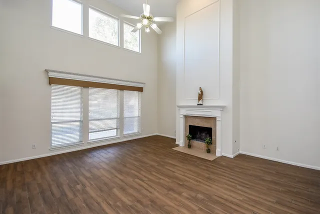 an empty room with wooden floor fireplace and windows