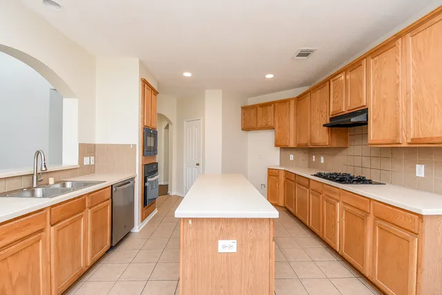 a large kitchen with stainless steel appliances granite countertop a sink and cabinets