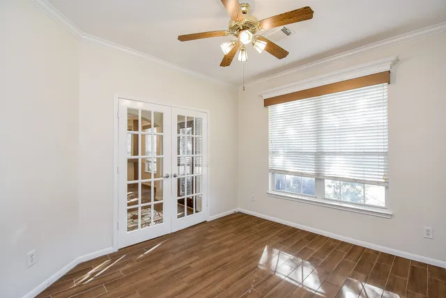 a view of an empty room with a window and wooden floor
