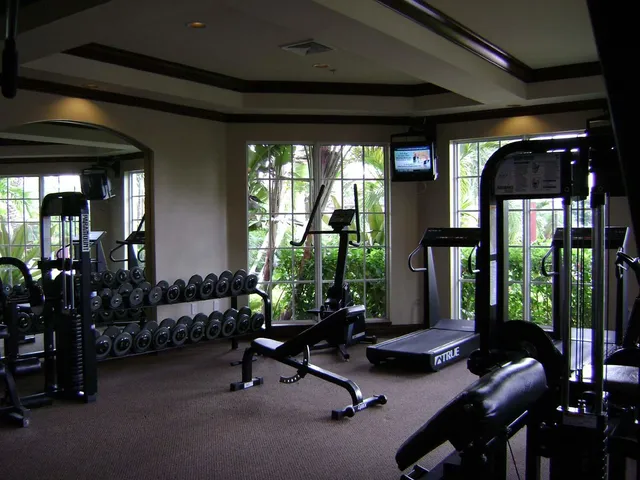 a living room with furniture gym equipment and floor to ceiling window