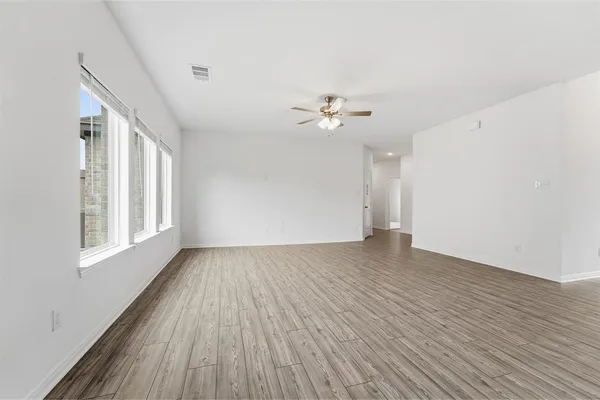 a view of an empty room with a window and wooden floor