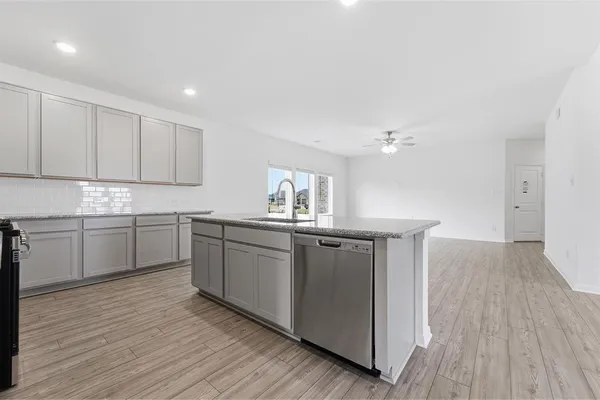 a kitchen with kitchen island granite countertop a sink cabinets and wooden floor