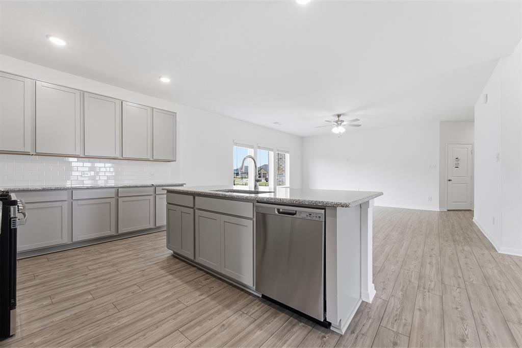 232 Triple Crown Road Waxahachie, TX 75165 - Photo 7 of 22 a kitchen with kitchen island granite countertop a sink cabinets and wooden floor