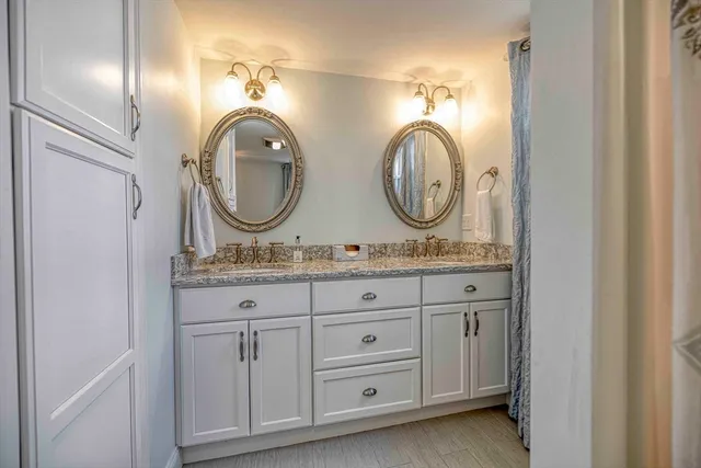 a bathroom with a granite countertop double vanity sink and a mirror