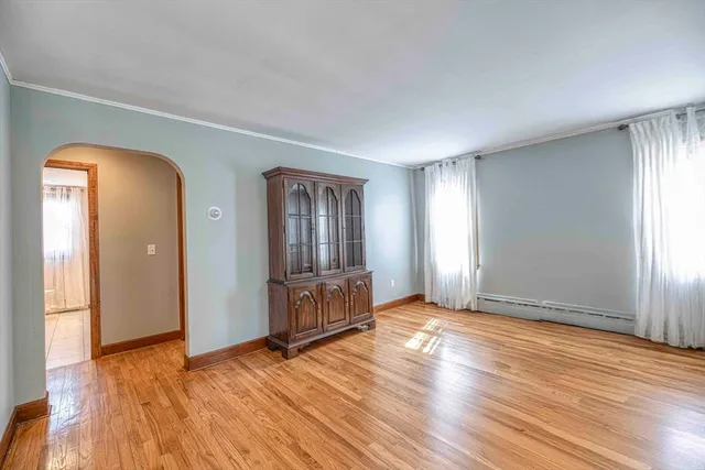 a view of empty room with wooden floor and window