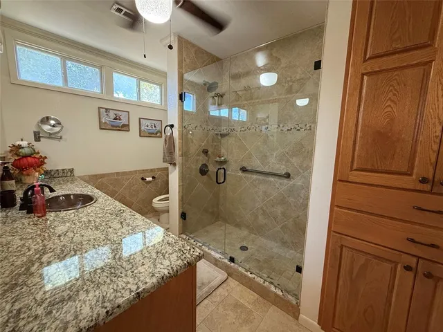 a bathroom with a granite countertop sink a mirror and shower