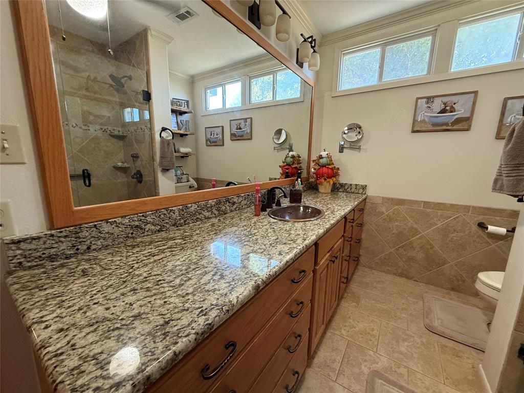 908 North Austin Street Comanche, TX 76442 - Photo 19 of 37 a bathroom with a granite countertop sink a mirror and shower