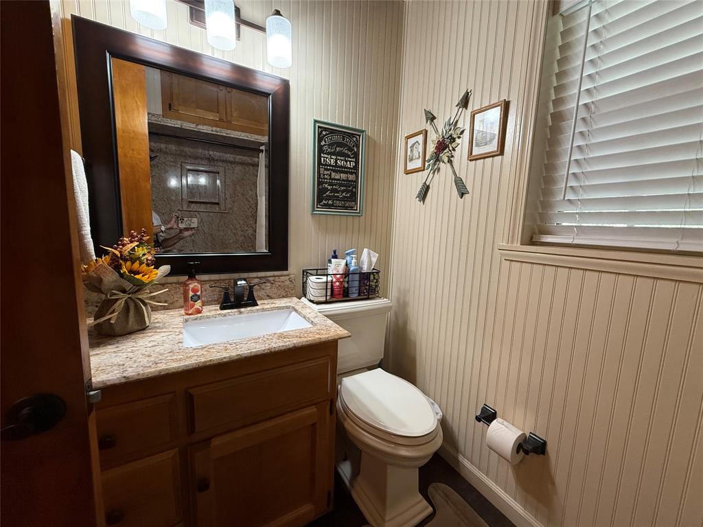 908 North Austin Street Comanche, TX 76442 - Photo 25 of 37 a bathroom with a granite countertop sink mirror vanity and toilet