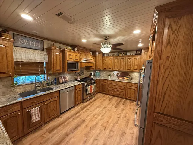 a large kitchen with a large counter top sink and stainless steel appliances