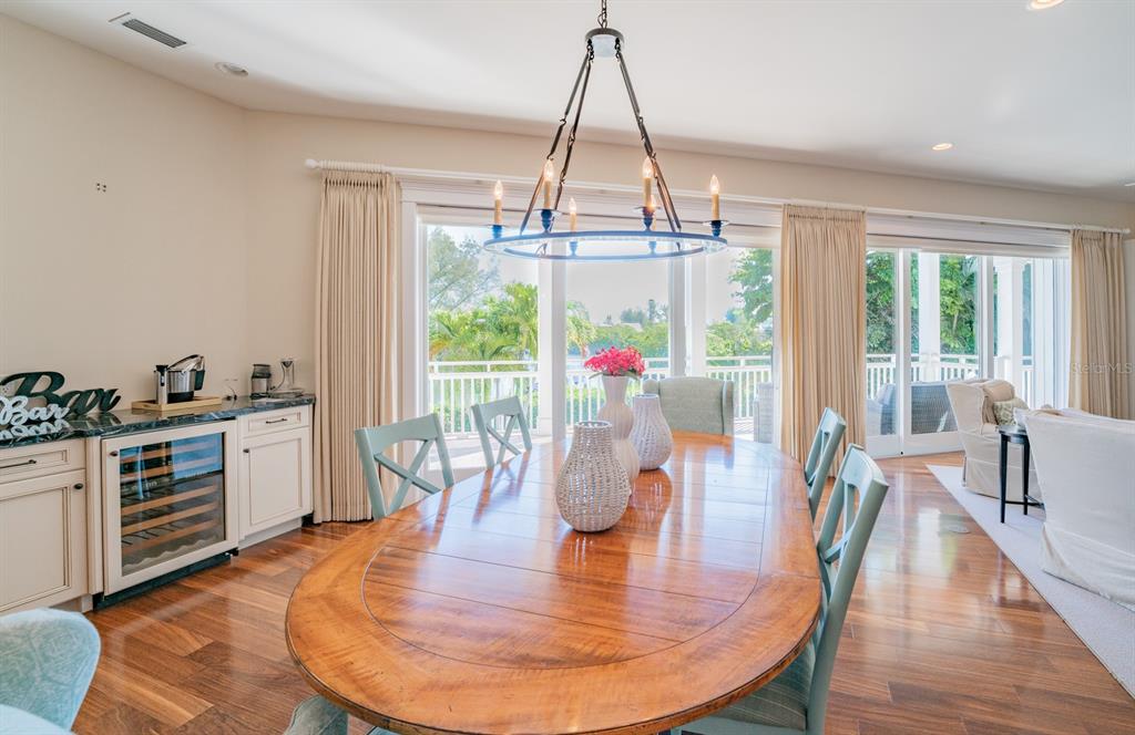 714 Jacaranda Road Anna Maria, FL 34216 - Photo 18 of 100 a dining room with wooden floor a chandelier a wooden table and chairs