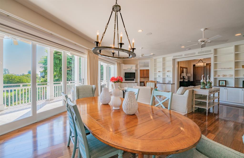 714 Jacaranda Road Anna Maria, FL 34216 - Photo 19 of 100 a dining room with wooden floor a chandelier a wooden table and chairs