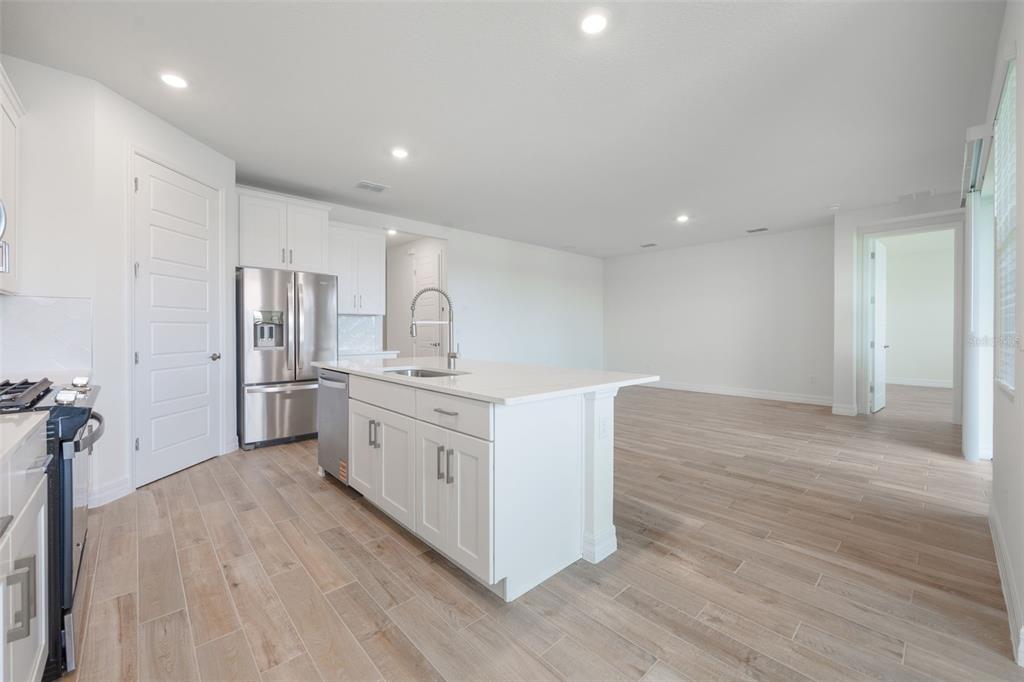 2277 Hamden Way Mount Dora, FL 32757 - Photo 16 of 32 a kitchen with white cabinets and stainless steel appliances