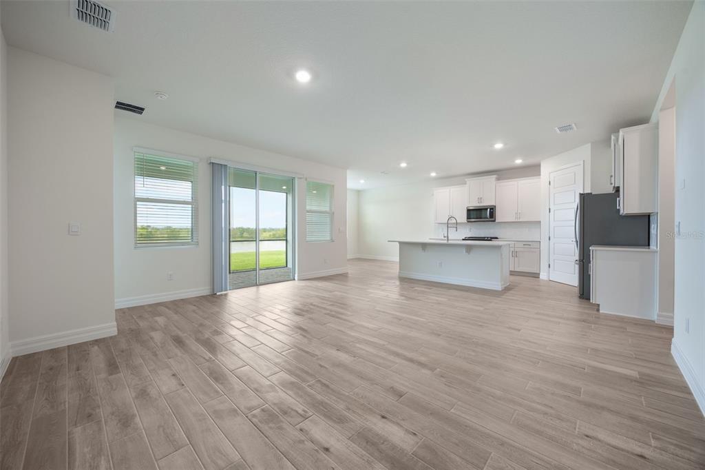 2277 Hamden Way Mount Dora, FL 32757 - Photo 18 of 32 a view of an empty room with wooden floor and a kitchen