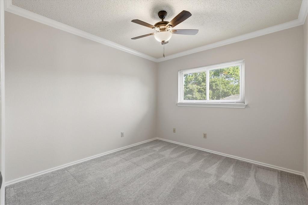318 Lodge Road Coppell, TX 75019 - Photo 29 of 35 A welcoming bedroom with crown molding, plush carpet, a ceiling fan and a wide window overlooking the outdoors.