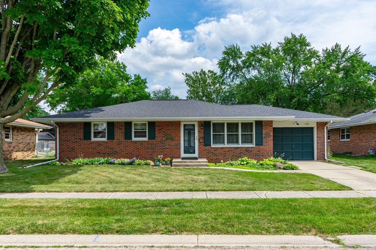a front view of a house with a garden and trees