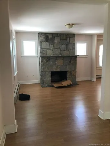an empty room with wooden floor fireplace and windows