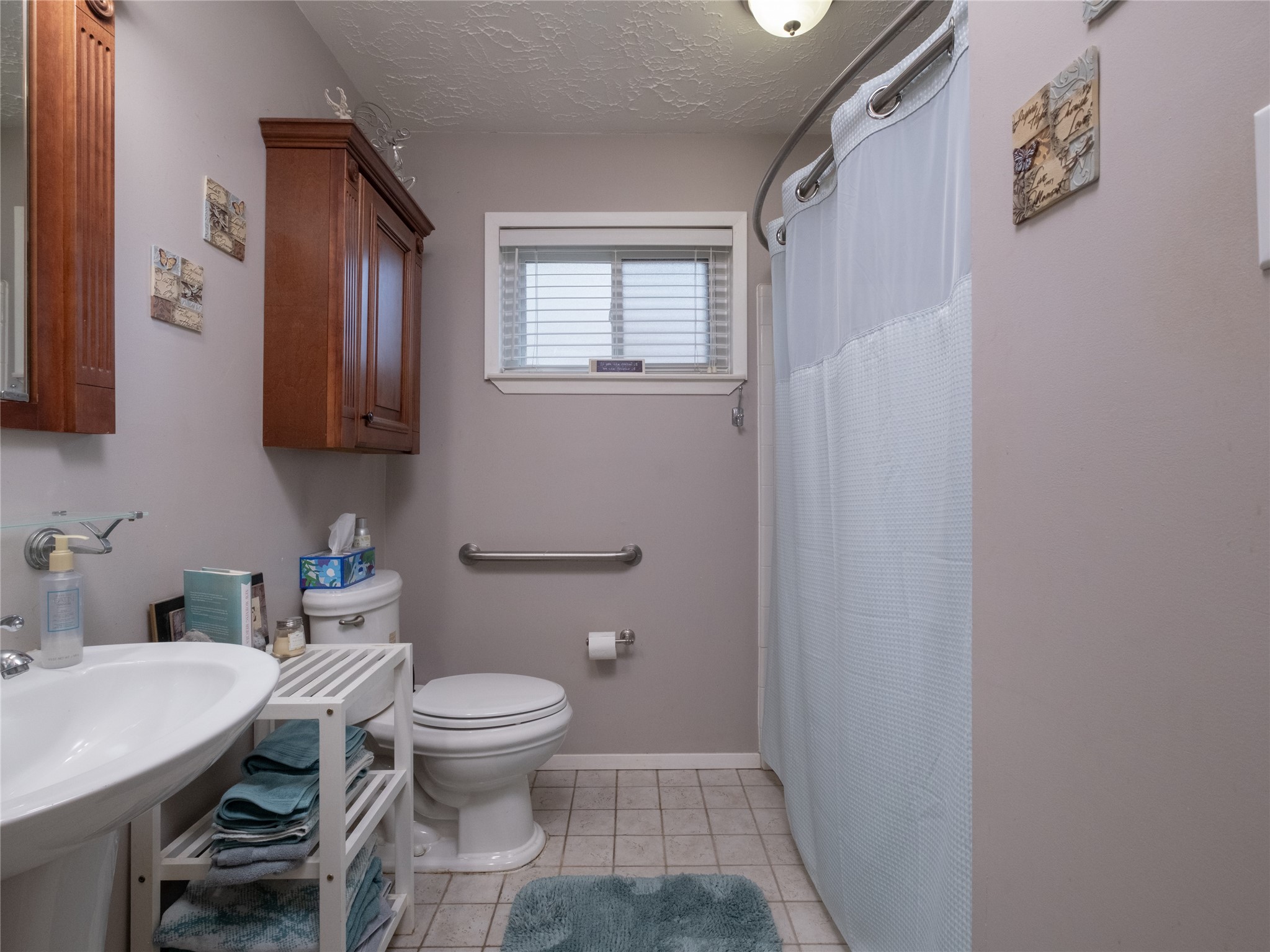 7315 Weatherhill Lane Houston, TX 77041 - Photo 18 of 40 Check out this cozy bathroom featuring a pedestal sink and a nice sized shower. There's a wall-mounted cabinet for storage. The window allows natural light to brighten the space.