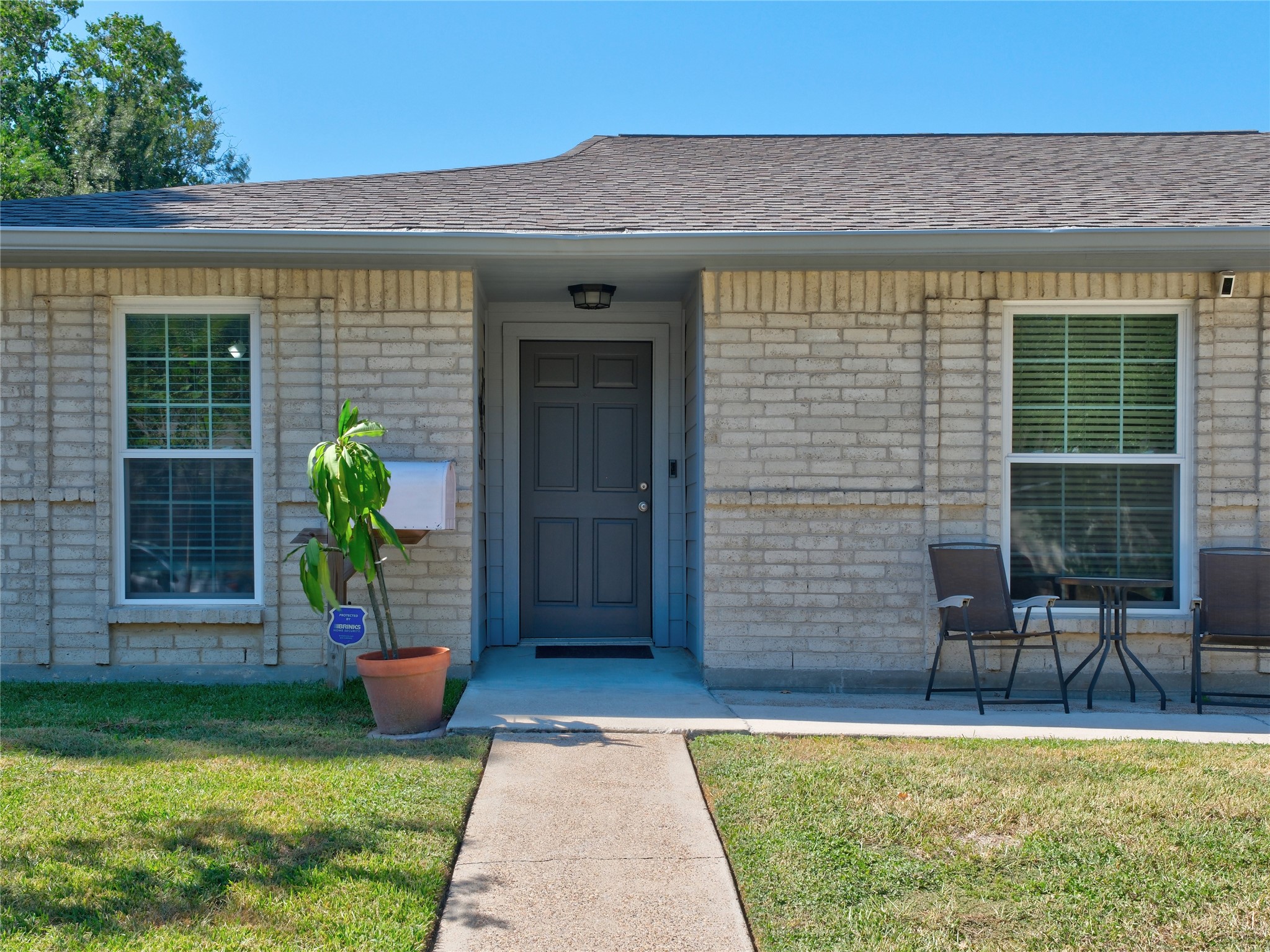 7315 Weatherhill Lane Houston, TX 77041 - Photo 2 of 40 Welcome home to this charming single-story home with a pretty front entrance, featuring a dark blue door, light brick exterior, and a cozy patio area to enjoy the weather. The front yard is landscaped with a small lawn and creates an inviting atmosphere.