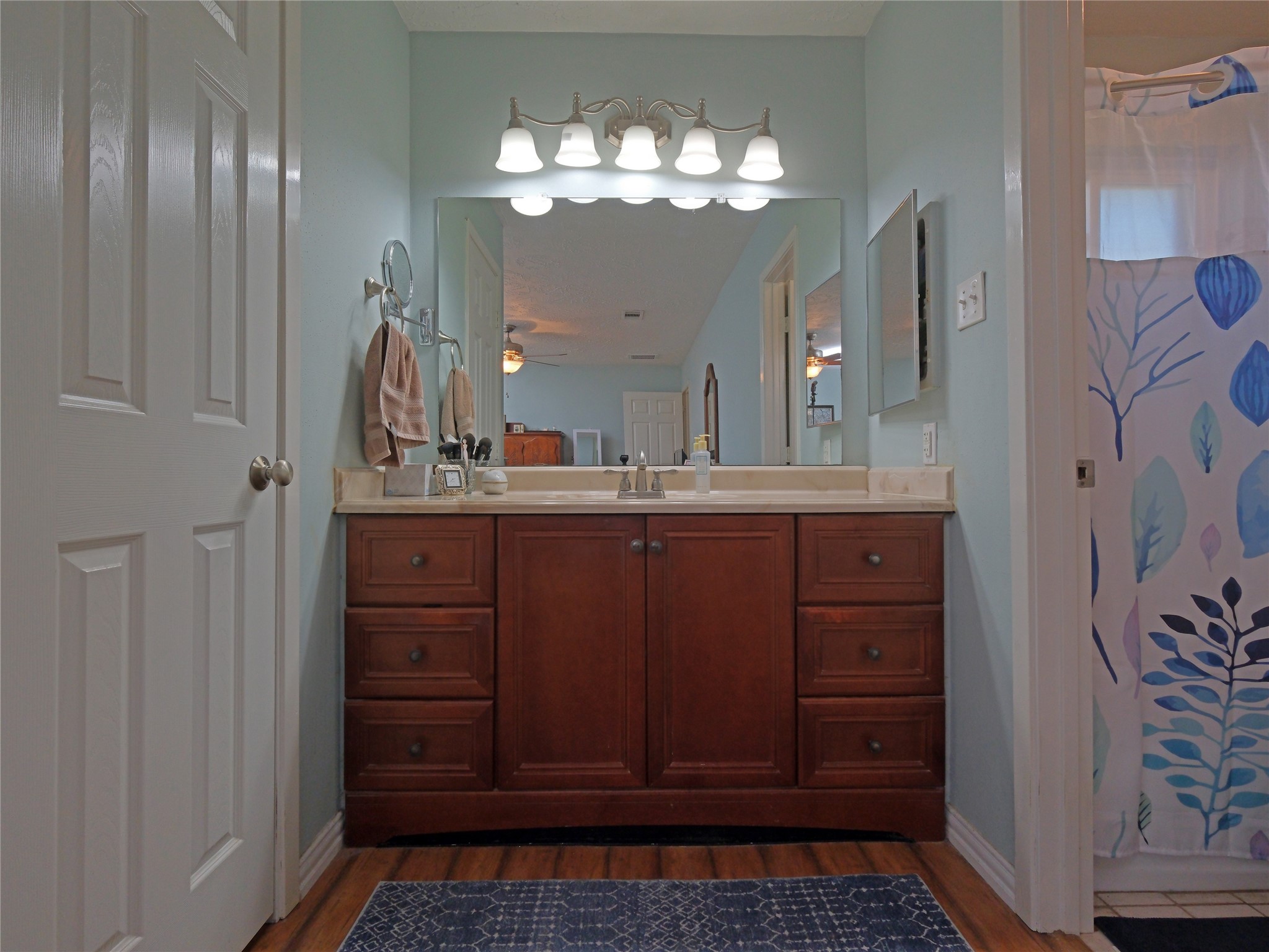 7315 Weatherhill Lane Houston, TX 77041 - Photo 27 of 40 This bathroom features a vanity with rich wood cabinets, a large mirror, and modern lighting. The walls are painted in a soft color.
