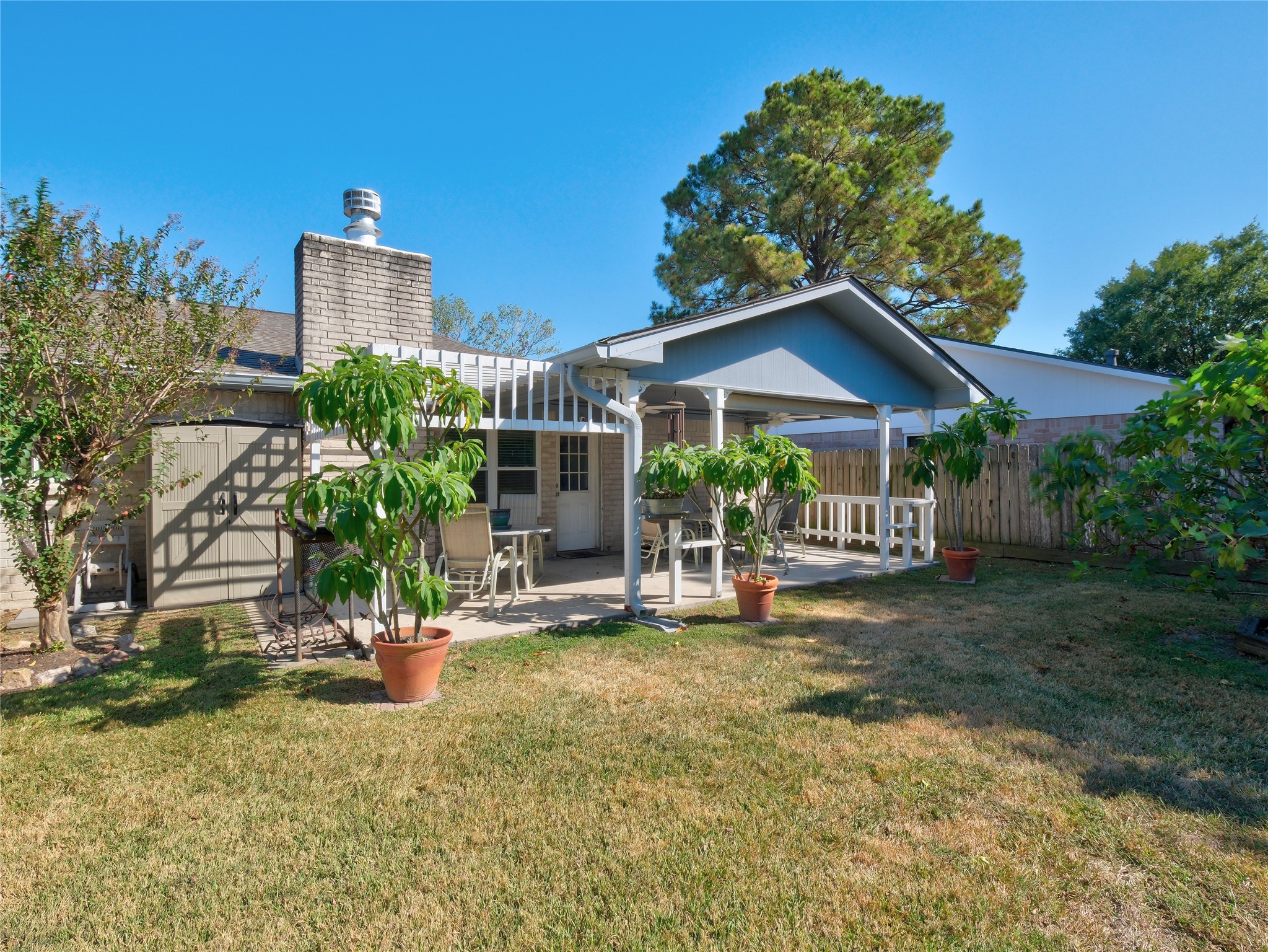 7315 Weatherhill Lane Houston, TX 77041 - Photo 36 of 40 This photo showcases a cozy backyard featuring a covered patio with outdoor seating and a well-maintained lawn, ideal for relaxation and entertaining.