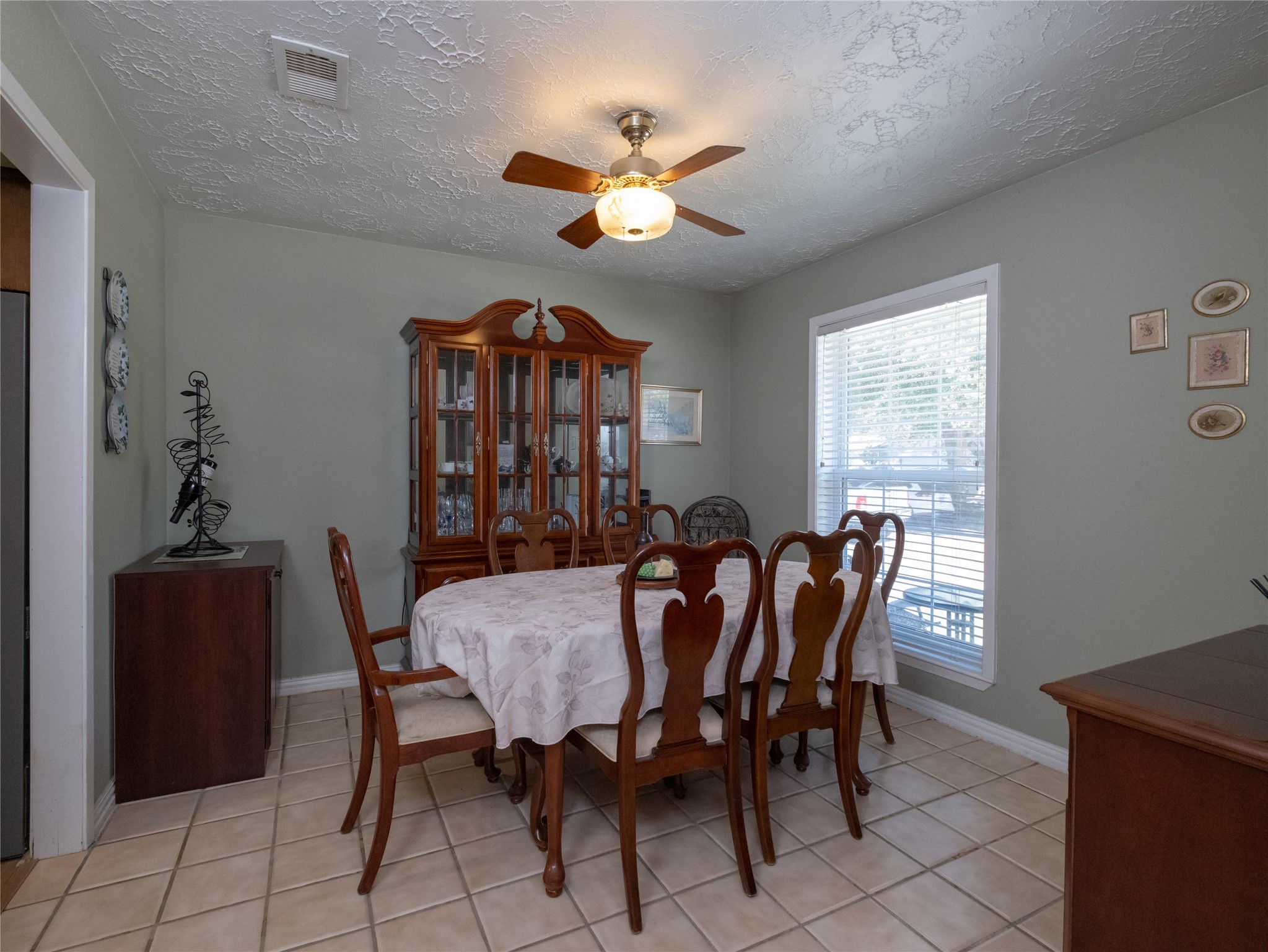 7315 Weatherhill Lane Houston, TX 77041 - Photo 6 of 40 This dining room features a cozy and traditional feel with natural light from a large window. The tiled floor complements the soft wall color, creating a welcoming atmosphere.