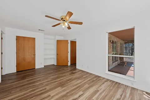 a view of empty room with wooden floor and ceiling fan