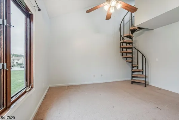 a view of an empty room with stairs and a window