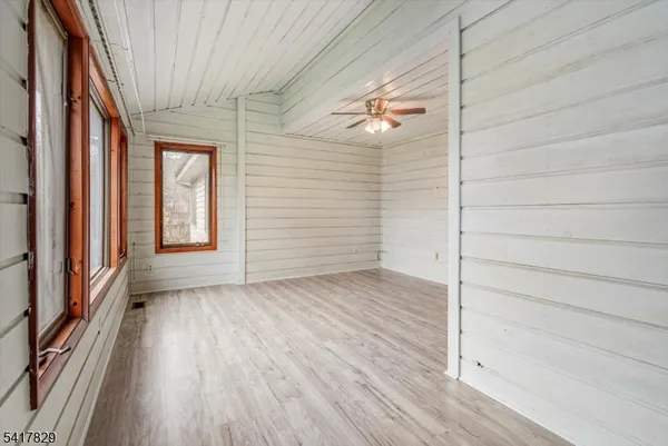 a view of an empty room with wooden floor and a ceiling fan