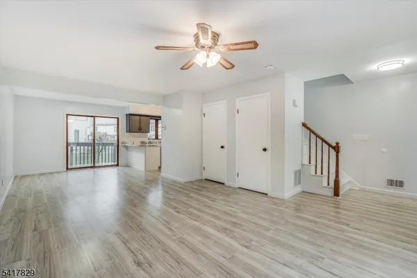 a view of an empty room with wooden floor and a ceiling fan