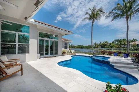 a view of a swimming pool with a bench and palm trees
