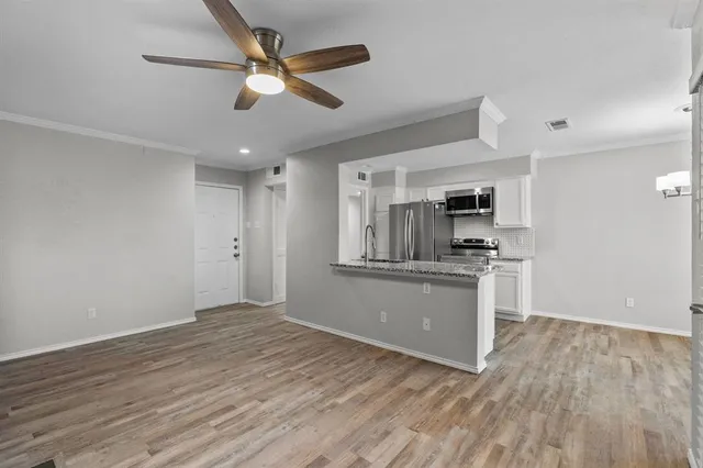 a view of kitchen and empty room with wooden floor