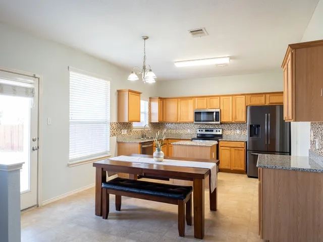 a kitchen with stainless steel appliances kitchen island granite countertop a refrigerator and a sink