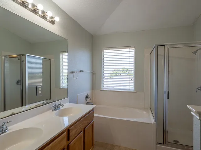 a bathroom with a tub double sink shower and a mirror