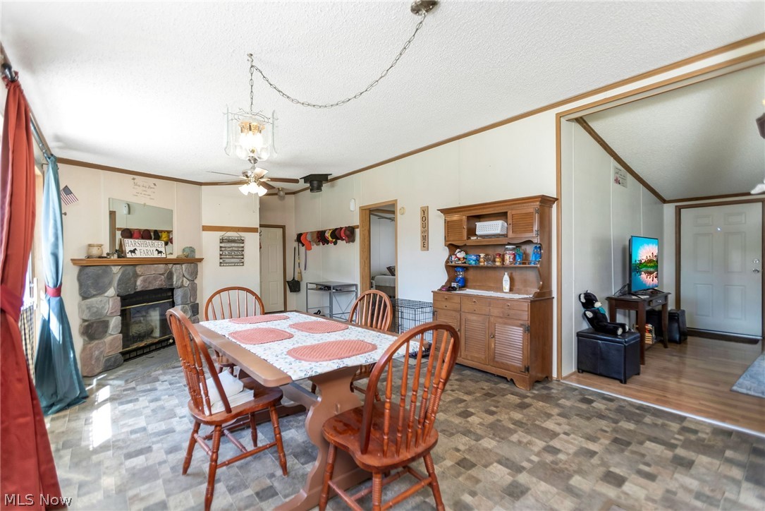 4502 Clover Road Cumberland, OH 43732 - Photo 14 of 38 Dining room with ceiling fan, a fireplace, crown molding, and a textured ceiling