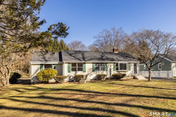 a front view of a house with large trees