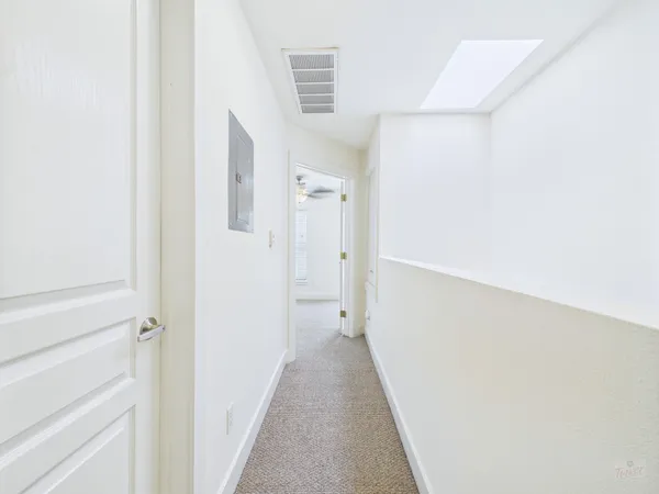 an empty room with a chandelier fan and windows