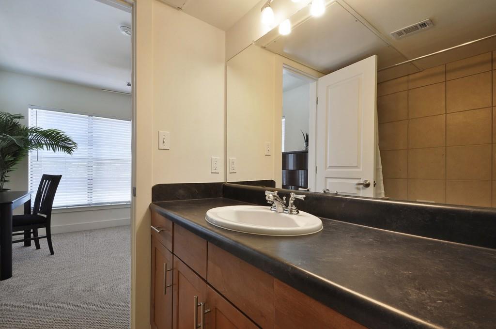 711 West 32nd Street, Unit 108 Austin, TX 78705 - Photo 21 of 28 a bathroom with a granite countertop sink a mirror and a bathtub