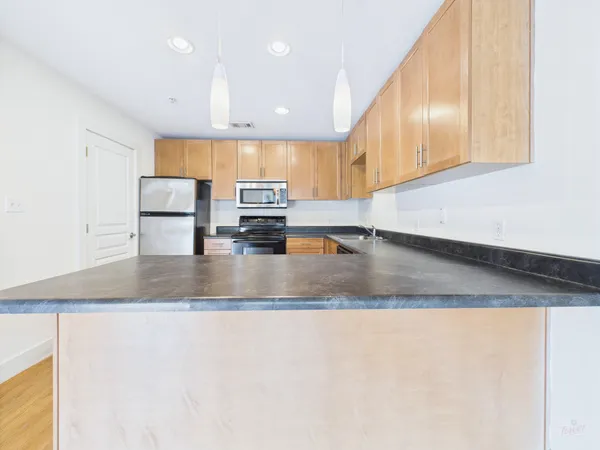 a view of a kitchen with stainless steel appliances granite countertop a sink a stove and a refrigerator